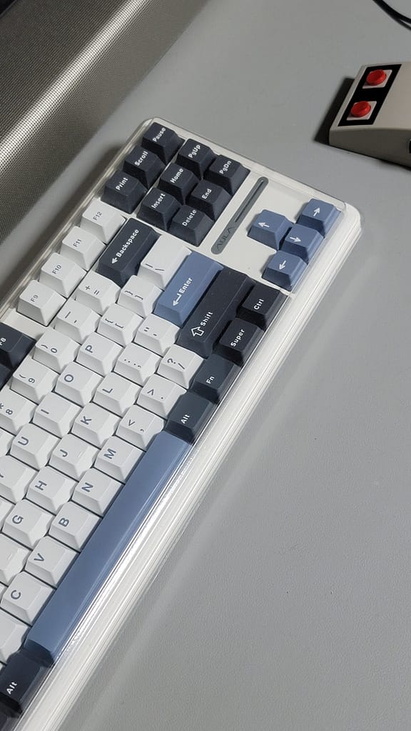 책상 위에 놓인 AULA F87 Pro 블루 블랙 화이트 키보드와 투명 루프